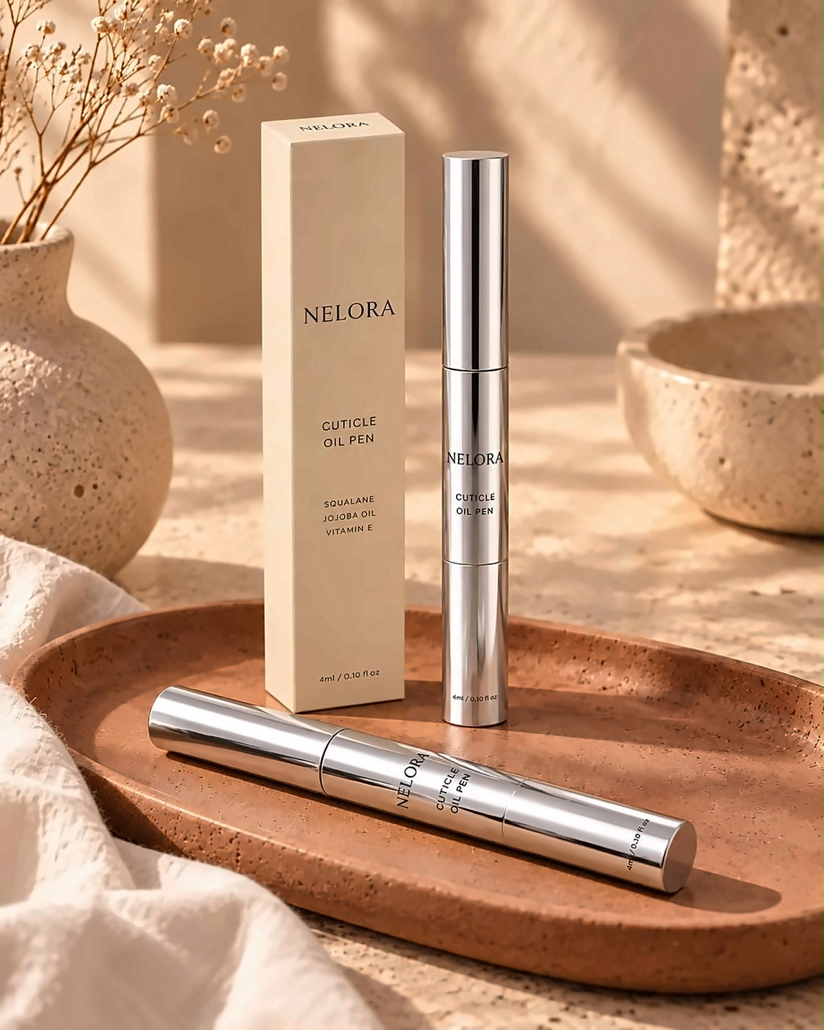 Two NELORA Cuticle Oil Pens and box on a terracotta tray